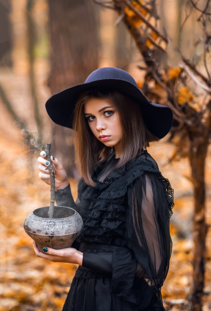 Foto retrato de uma menina em um vestido preto em uma floresta de outono. uma jovem bruxa.