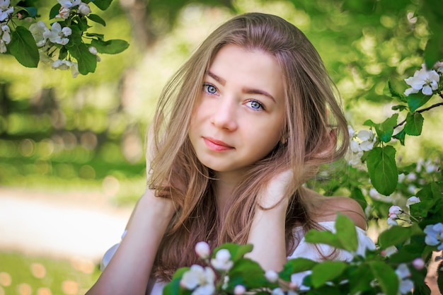 Retrato de uma menina em uma macieira de florescência.