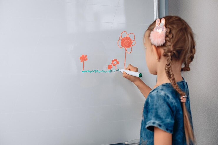 Retrato de uma menina encantadora criança simpática, desenhando uma pequena imagem em um quadro branco com marcadores. Conceito de desenvolvimento. foto com ruído