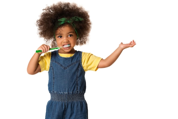 Foto retrato de uma menina escovando os dentes enquanto está de pé contra um fundo branco