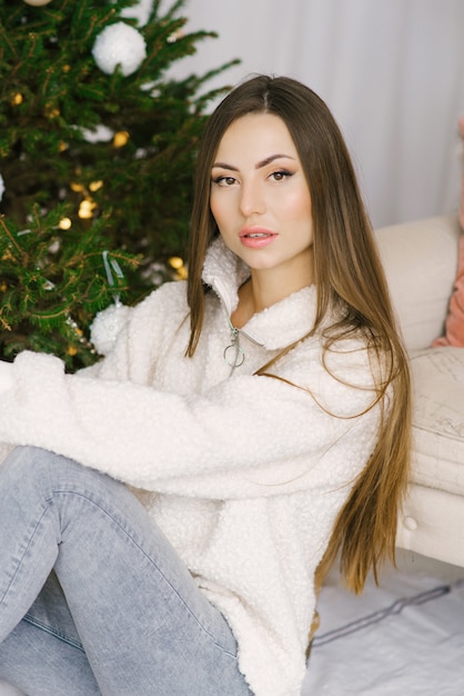 Retrato de uma menina estilosa com cabelo comprido perto da árvore de Natal