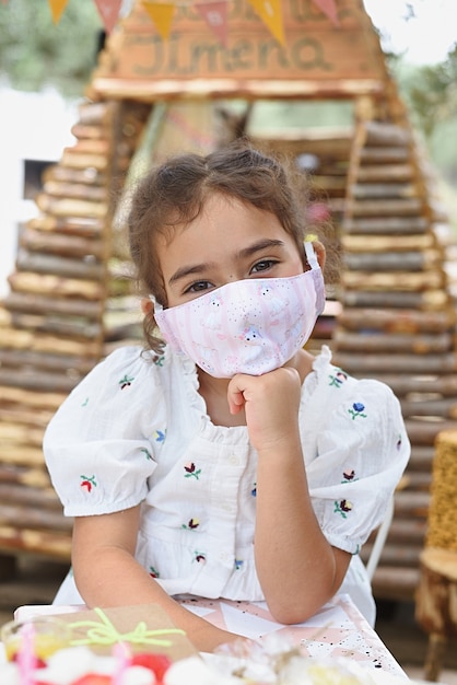 Retrato de uma menina feliz brincando com uma máscara de proteção viral.