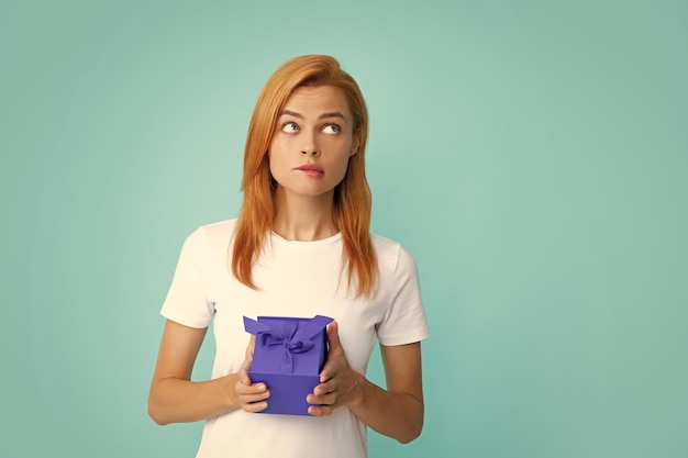 Retrato de uma menina feliz com caixa de presente isolada sobre fundo azul Mulher segurando o presente presente