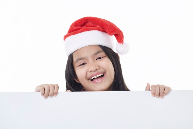 Retrato de uma menina feliz com chapéu de papai noel segurando um quadro em branco