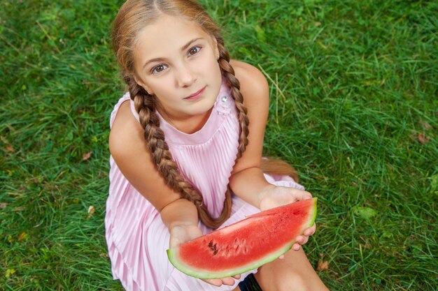 Retrato de uma menina feliz com melancia desfrutando de verão ao ar livre durante o dia.