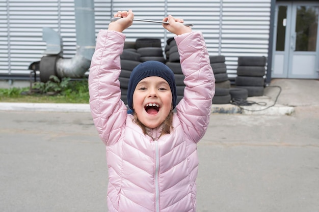Retrato de uma menina feliz com uma chave inglesa no fundo do serviço de reparo da garagem