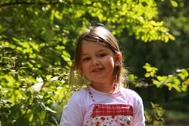 Retrato de uma menina feliz contra plantas em um dia ensolarado