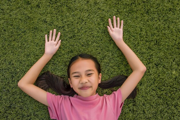 Foto retrato de uma menina feliz deitada em um campo gramado