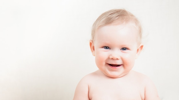 Retrato de uma menina feliz e sorridente em um fundo branco claro.