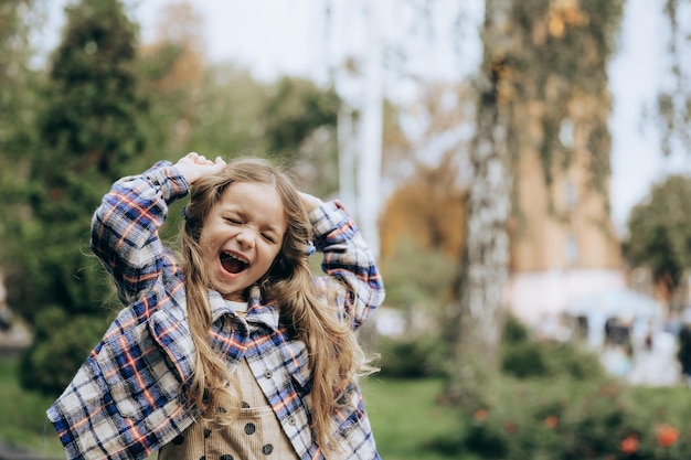 Retrato de uma menina feliz e sorridente posando para uma foto durante uma caminhada de verão na cidade