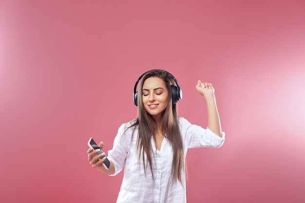 Retrato de uma menina feliz ouvindo música com fones de ouvido sem fio em um smartphone