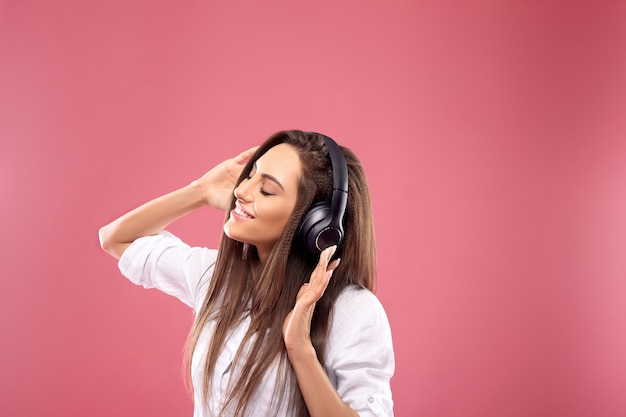 Retrato de uma menina feliz ouvindo música com fones de ouvido sem fio em um smartphone