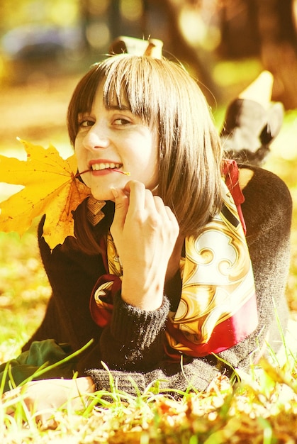 Retrato de uma menina feliz sem maquiagem deitada no chão em um parque de outono