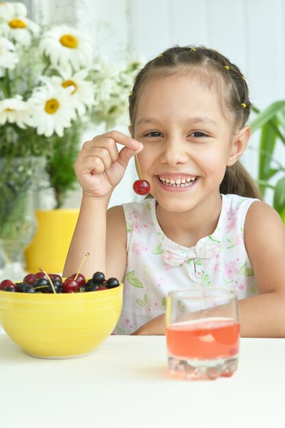 Foto retrato de uma menina fofa comendo cerejas