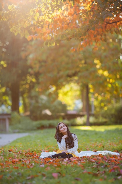 Retrato de uma menina linda de 9 anos com longos cabelos escuros em roupas brilhantes Criança feliz no parque de outono