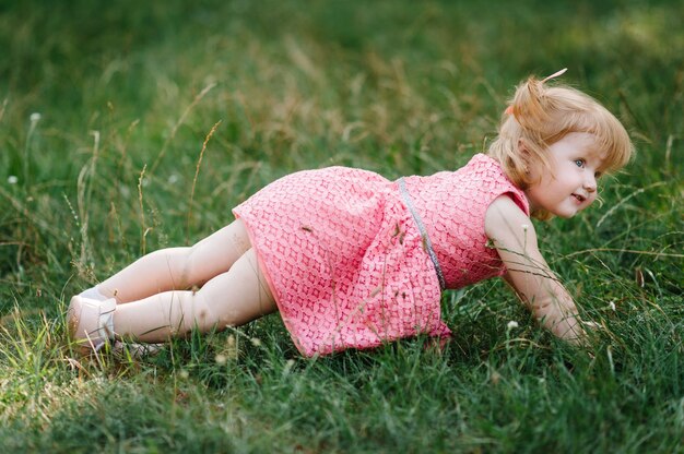 Retrato de uma menina linda na natureza nas férias do dia de verão. O jogo no parque na hora do pôr do sol. Fechar-se. O conceito de férias em família e de tempo juntos.