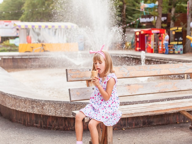 Retrato de uma menina loira bonita com sorvete em um passeio no parque.