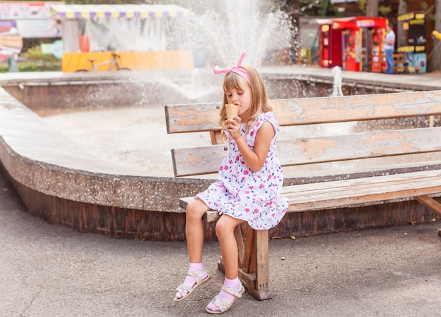 Retrato de uma menina loira bonita com sorvete em um passeio no parque.