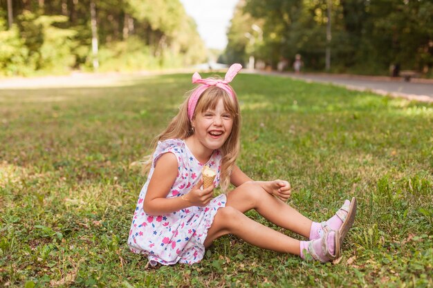 Retrato de uma menina loira bonita com sorvete em um passeio no parque.