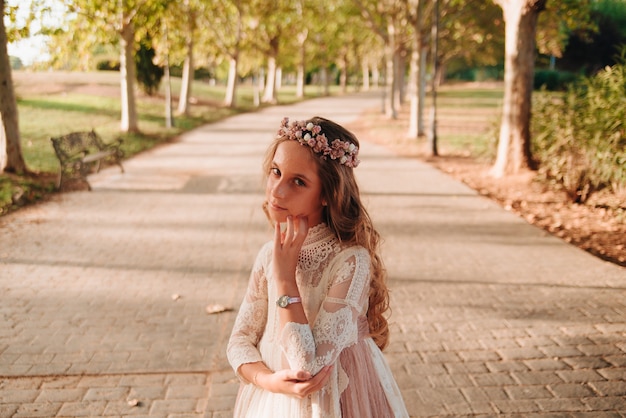 Retrato de uma menina loira com cabelo encaracolado vestida com vestido de comunhão