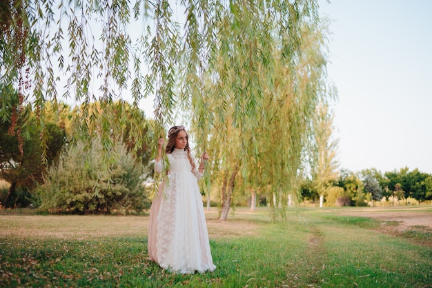 Foto retrato de uma menina loira com cabelo encaracolado vestida com vestido de comunhão