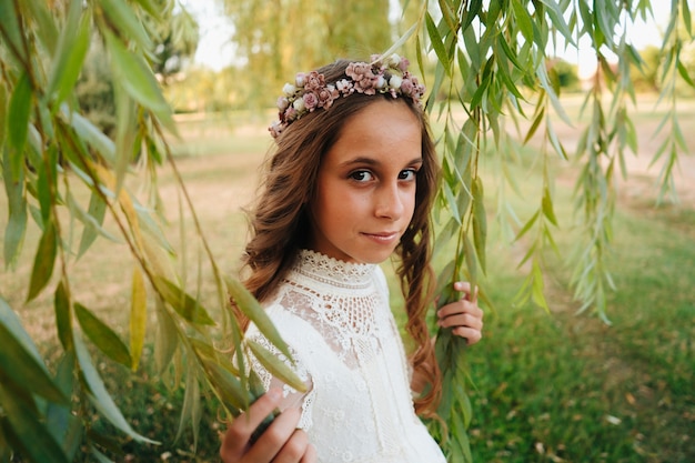 Retrato de uma menina loira com cabelo encaracolado vestida com vestido de comunhão