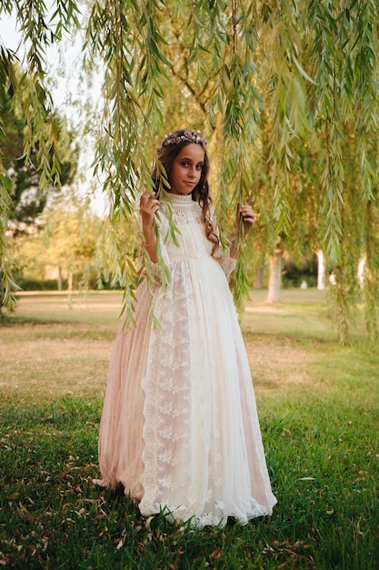 Foto retrato de uma menina loira com cabelo encaracolado vestida com vestido de comunhão