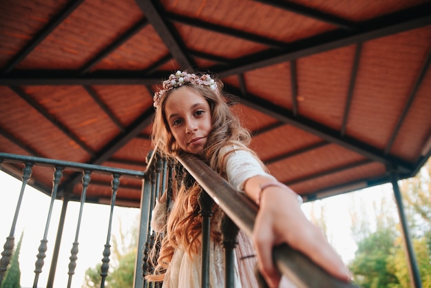 Retrato de uma menina loira com cabelos cacheados, vestida com um vestido de comunhão. copiar espaço