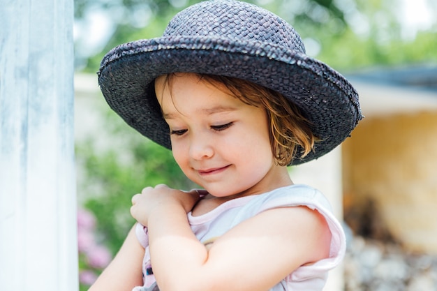 Retrato de uma menina loira com chapéu de palha azul sorrindo