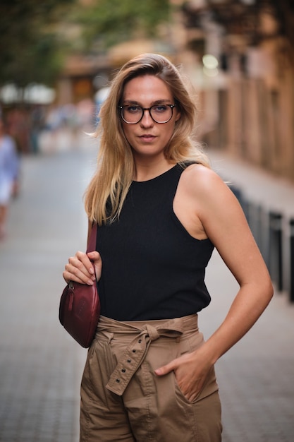 Retrato de uma menina loira de óculos posando para uma sessão de fotos em uma rua da cidade de Barcelona.