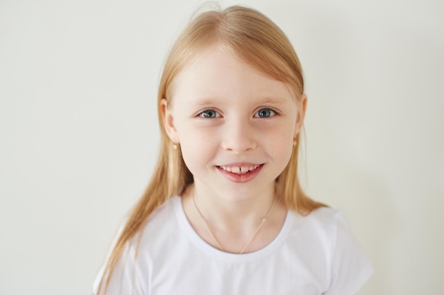 Retrato de uma menina loira em um fundo branco em uma camiseta branca