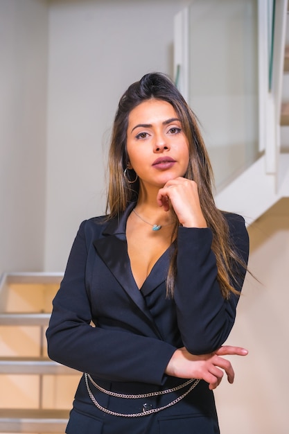 retrato de uma menina morena caucasiana em um elegante terno preto posado nas escadas de um hotel, fotografia de moda