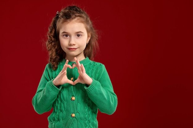 Retrato de uma menina morena com um cabelo longo e encaracolado posando contra um fundo vermelho