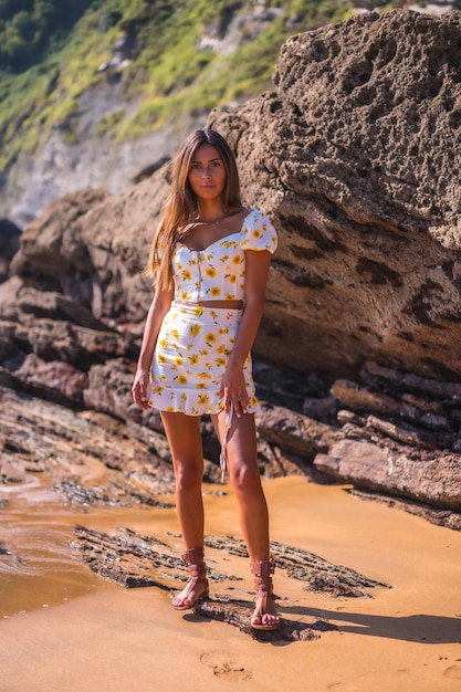 Retrato de uma menina morena em um vestido branco na praia aproveitando o verão