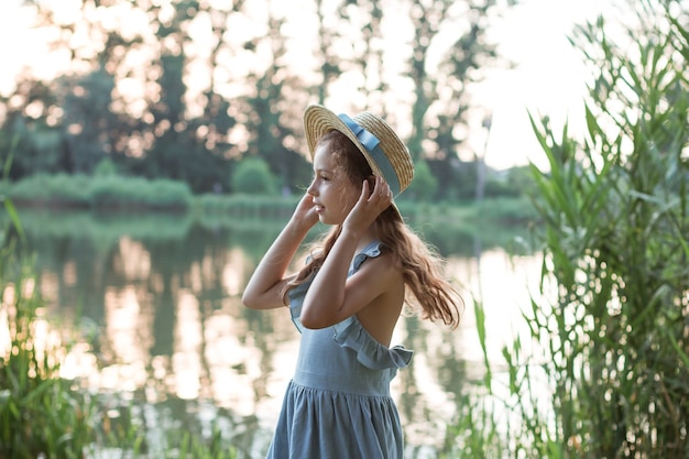 retrato de uma menina no parque com árvores de junco verde e um lago no verão