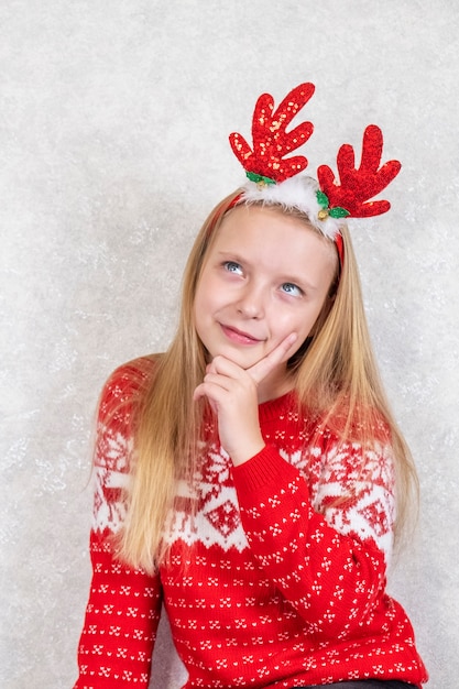 Retrato de uma menina pensativa em um aro de cabelo de Natal