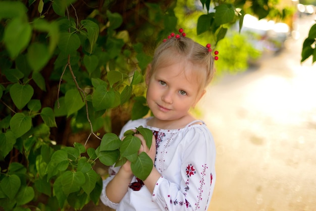 Retrato de uma menina perto da árvore em uma camisa bordada ucraniana Viburnum no cabelo