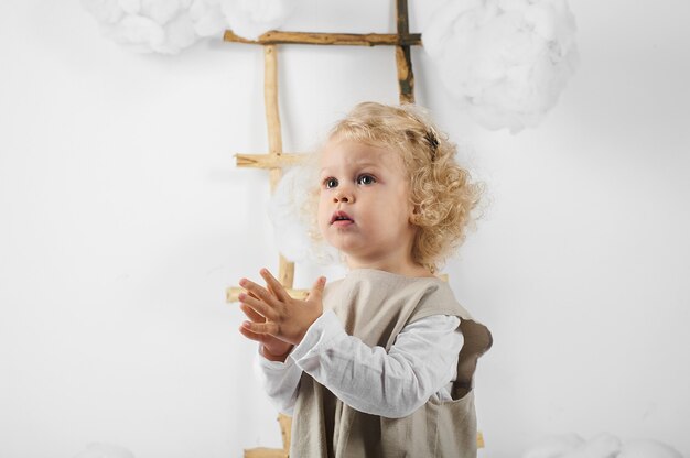 Retrato de uma menina perto da escada no meio das nuvens em um fundo branco