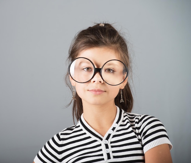 Foto retrato de uma menina pré-adolescente em óculos studio shot fundo cinza