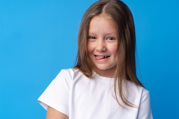 Retrato de uma menina pré-adolescente sorridente em fundo azul
