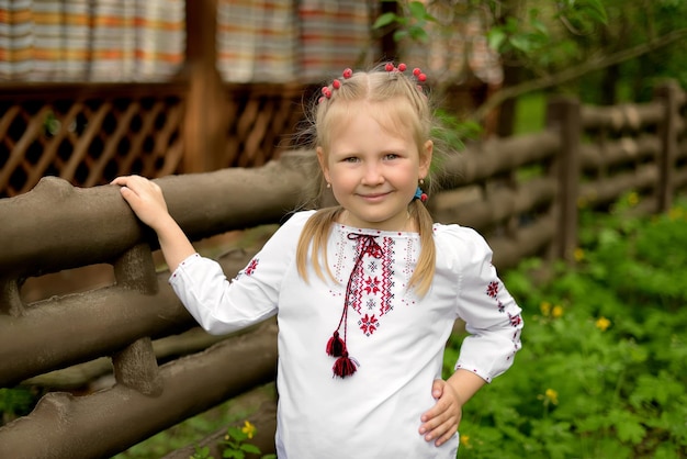 Retrato de uma menina pré-escolar com flores em uma camisa bordada ucraniana Viburnum no cabelo