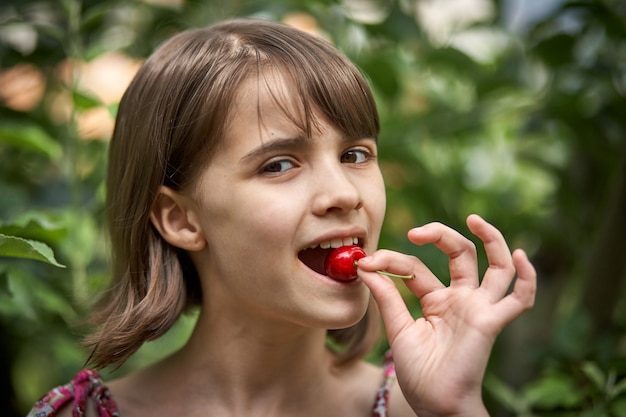 Retrato de uma menina rindo comendo cerejas no jardim