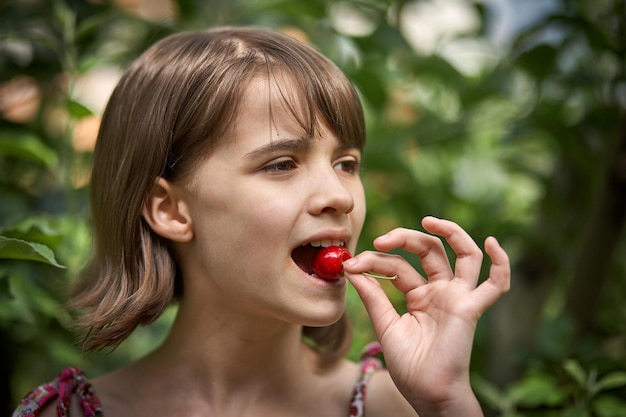 Retrato de uma menina rindo comendo cerejas no jardim