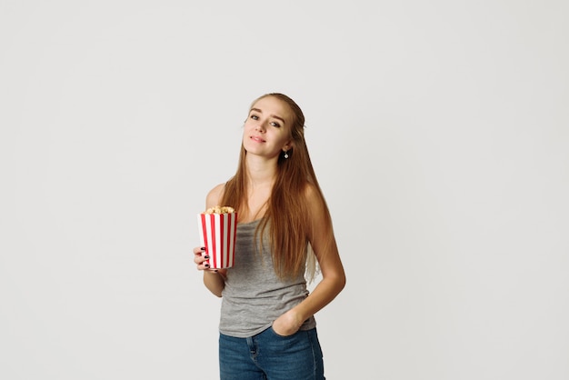 Retrato de uma menina rindo em roupas casuais, segurando a caixa de pipoca.