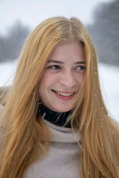 Retrato de uma menina ruiva com sardas no rosto com fundo de neve turva