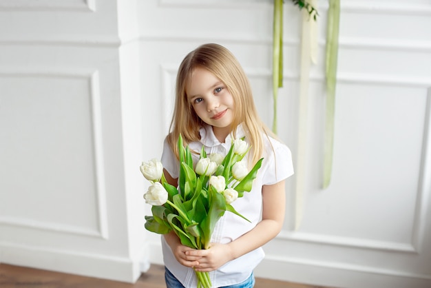 Retrato de uma menina segurando um buquê de tulipas brancas.