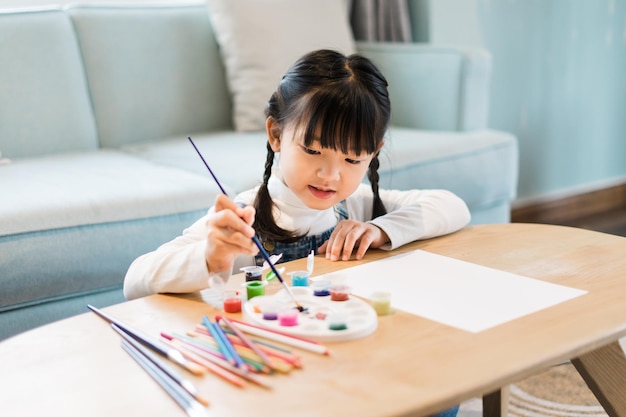 Retrato de uma menina sentada e pintando em casa