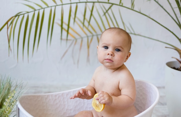 Retrato de uma menina sentada em uma banheira branca sobre um fundo branco