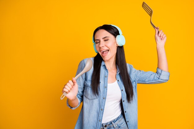 Retrato de uma menina sonhadora muito alegre ouvindo som estéreo usando uma colher como o microfone