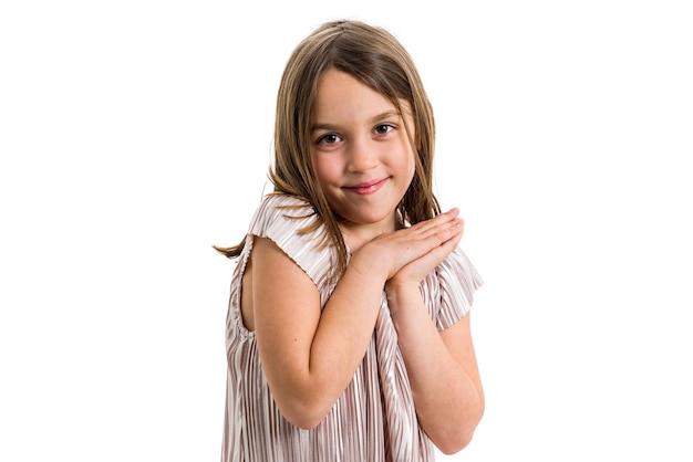 Foto retrato de uma menina sorridente com as mãos apertadas contra um fundo branco